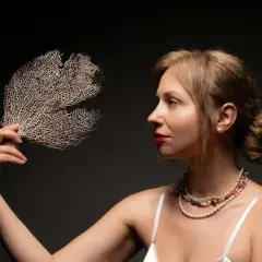 Kobieta z biżuterią i wachlarzem z koralu naturalnego.