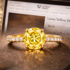 Złoty pierścionek z olśniewającym, żółtym diamentem i brylantami. Na ekranie laptopa widnieje napis "Loose Yellow Diamond".