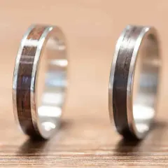 Dwie obrączki z metalu i drewna na drewnianym tle.