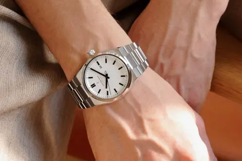 Elegancki zegarek na metalowej bransolecie na męskim nadgarstku. Klasyczny design, na której ręce nosi się zegarek, podkreśla styl.