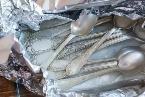 Stare, ozdobne łyżki w folii aluminiowej, gotowe do czyszczenia srebra solą.