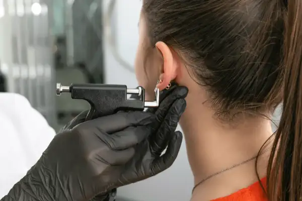 Przekłuwanie ucha, które może powodować ból ucha po przekłuciu chrząstki.
