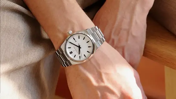 Elegancki zegarek na metalowej bransolecie na męskim nadgarstku. Klasyczny design, na której ręce nosi się zegarek, podkreśla styl.
