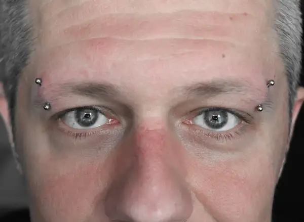 Zbliżenie na twarz z kolczykami w brwiach. Zastanawiasz się, ile kosztuje nostril?