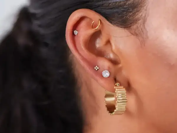 Ucho ozdobione kilkoma kolczykami, w tym subtelnym anti tragus piercing z małym kamieniem.